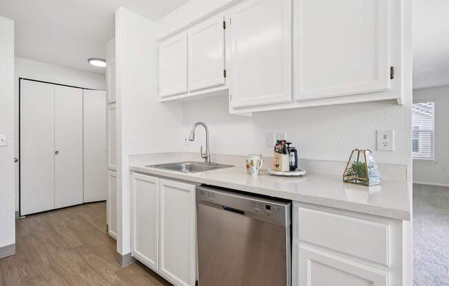 A kitchen with white cabinets and a stainless steel dishwasher.