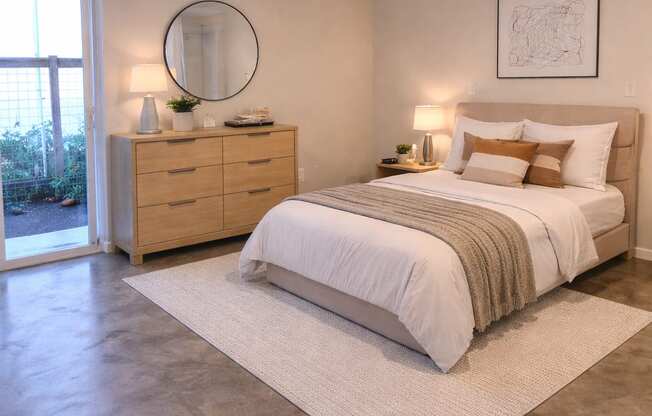 A bedroom with a large bed and a dresser with a mirror.