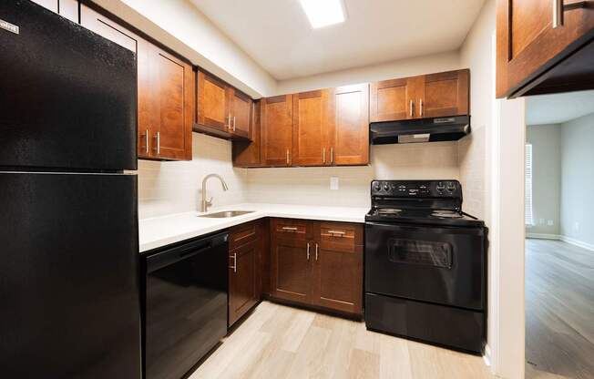 A black refrigerator is in a kitchen with wooden cabinets.