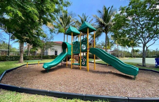A playground with a green slide and a yellow structure.