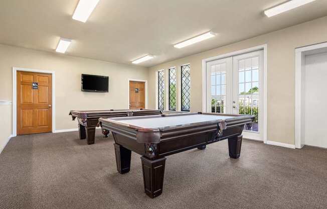 A room with a pool table and a television mounted on the wall.