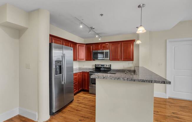 A kitchen with a refrigerator, microwave, oven, and sink.
