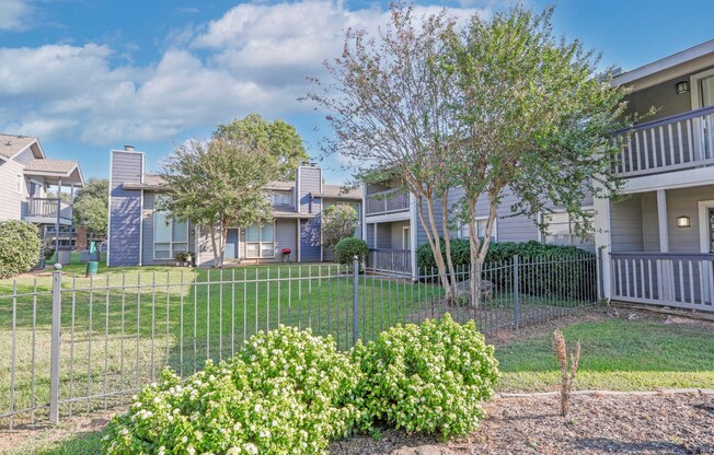 Lush landscaping with apartment buildings in the background at Laurel Parc apartments in Shreveport, LA.
