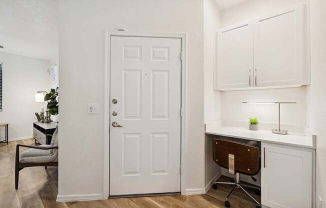 A white door is in a room with a desk and chair.