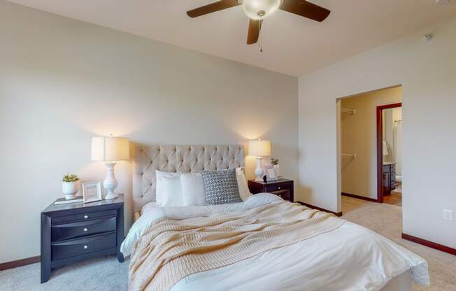 a bedroom with white walls and a ceiling fan