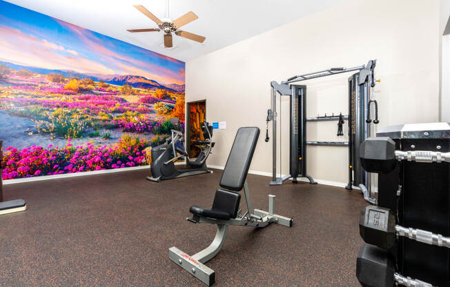 a gym with exercise equipment and a painting of flowers on the wall