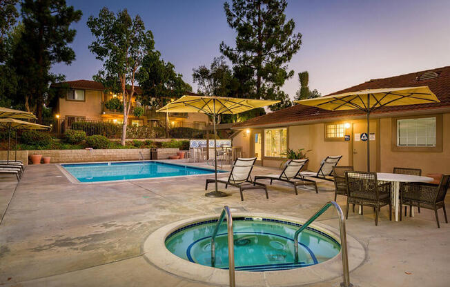 A pool with a hot tub and chairs around it.