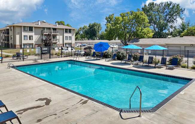 A swimming pool surrounded by chairs and umbrellas.