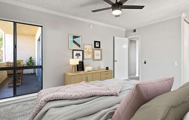 Carpeted bedroom with ceiling fan and natural light from adjacent patio.