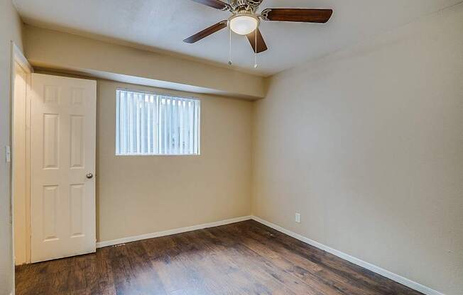 A room with a ceiling fan and a door.