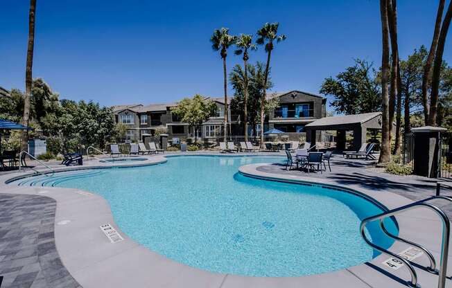 A large swimming pool surrounded by palm trees and lounge chairs.