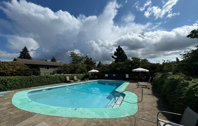 a pool with chairs and umbrellas and a cloudy sky