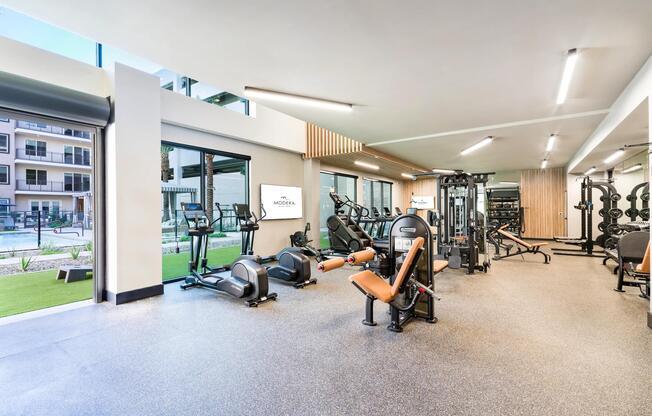 Floor-to-ceiling windows and open views of the pool bring natural light into this well-equipped fitness studio designed for all workout styles.
