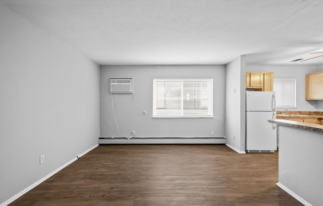 the living room and kitchen of an apartment with wood flooring and white walls