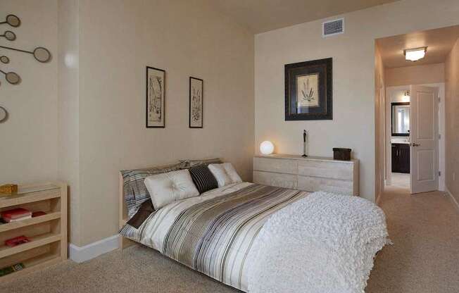 A bedroom with plush carpet flooring, high ceilings, natural light, and access to a private bathroom.