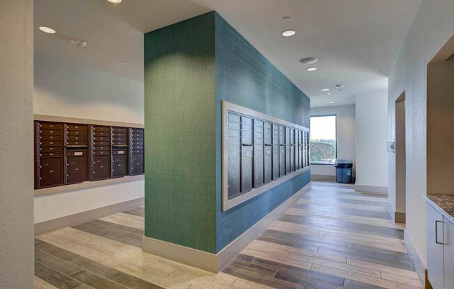 A long hallway with a green wall and a trash can in the distance.