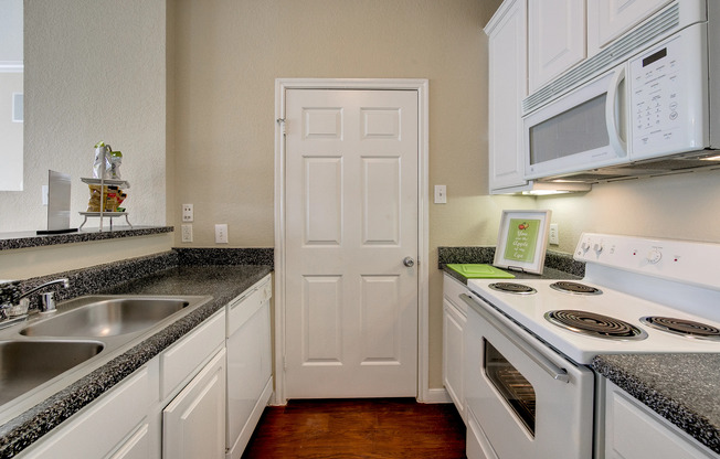 View of Classic Apartment Interior, Showing Kitchen with Gas Appliances, Pantry, and Plank Wood Flooring at Stonebriar of Frisco Apartments