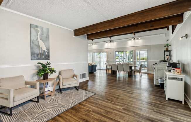 the living room and dining area of a home with a wood floor and white walls