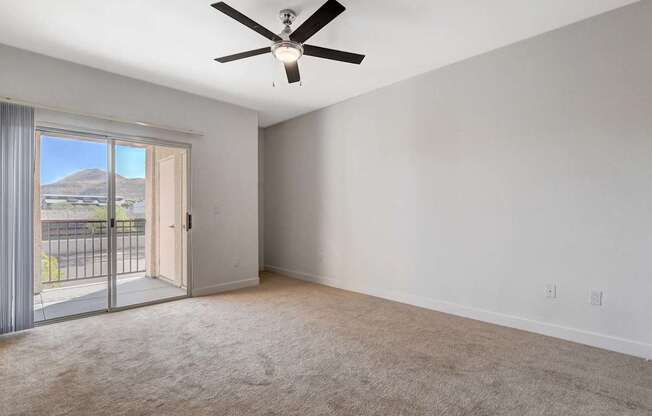 A room with a ceiling fan and sliding glass doors.
