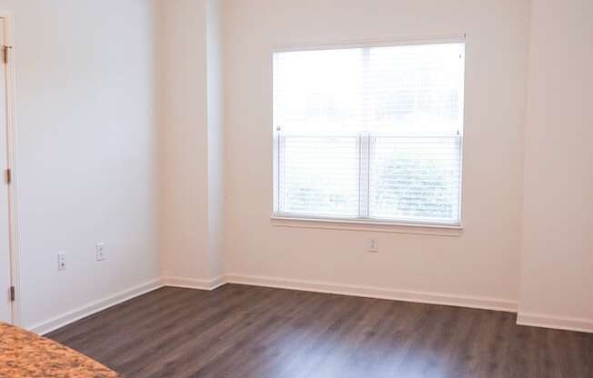 an empty living room with a large window and wooden floors