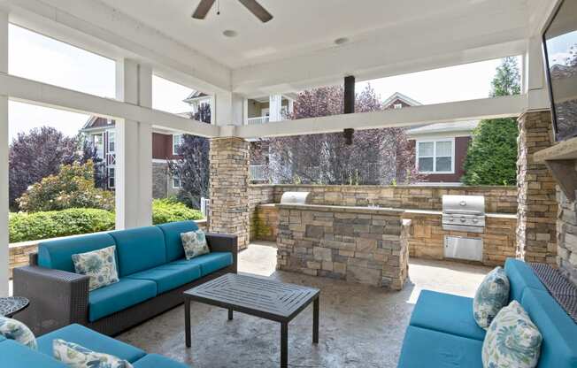 a covered patio with blue couches and a stone wall