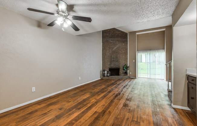 an empty living room with wood flooring and a ceiling fan