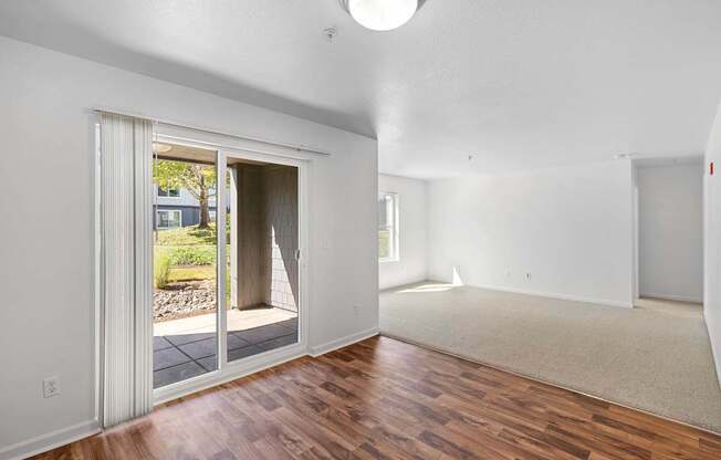 the living room and dining room of an empty house with a door to a patio