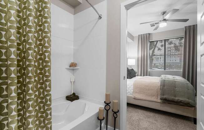 A bathroom with a shower, a bed, and a window.