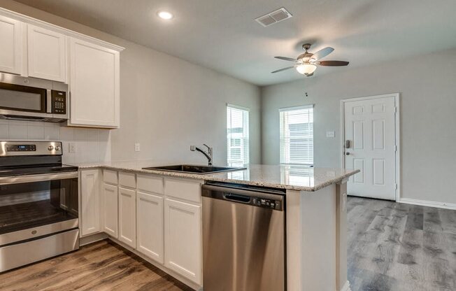 a kitchen with an island and a stove and a ceiling fan