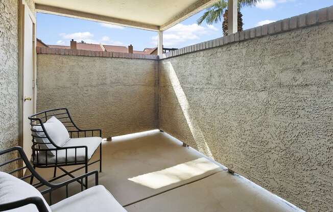 a balcony with chairs and a table and a wall with a palm tree