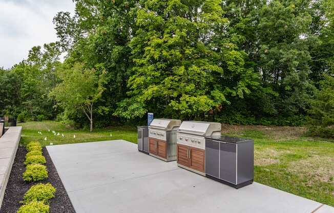 A large outdoor grill is in the middle of a concrete patio.