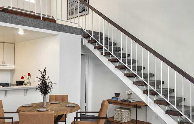 a living room with a staircase and a table and chairs