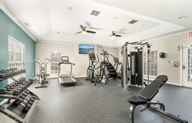 a gym with weights and cardio equipment on the floor and a window
