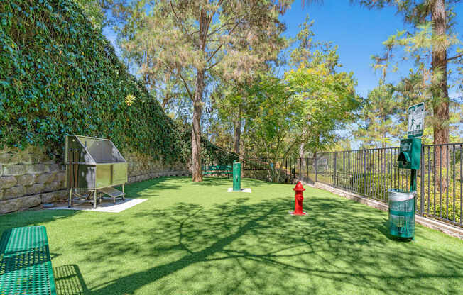 A green lawn with a red fire hydrant and a green trash can.
