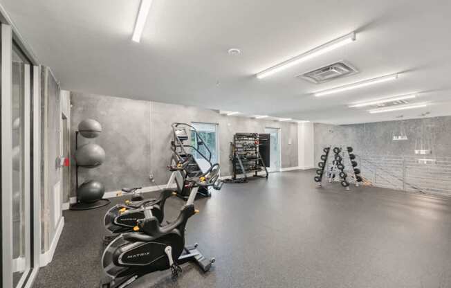 A gym with exercise equipment and a mirror on the wall.