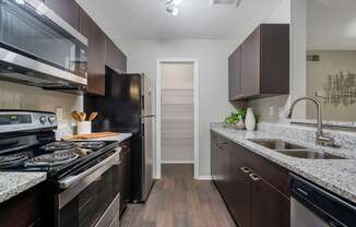 A kitchen with dark wood cabinets and a black stove top oven.