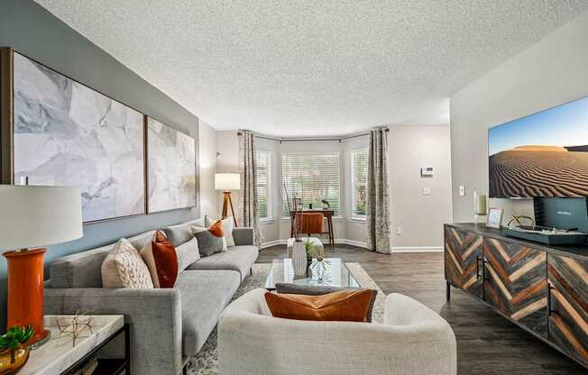 A living room with a grey couch, a white armchair, and a wooden coffee table.