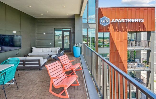 a balcony with a couch and chairs and a television at Link Apartments Innovation Quarter, Winston Salem, NC, 27101