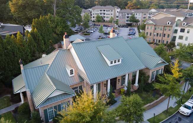 A house with a green roof is surrounded by trees and other houses.