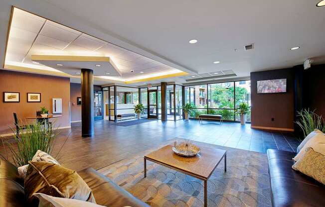 A lobby with a brown leather couch and a coffee table.