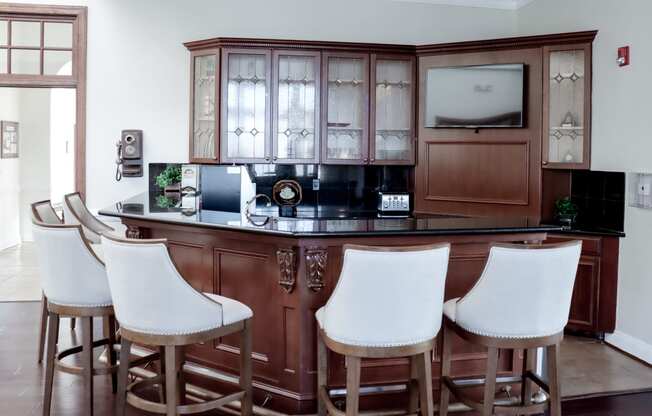 a bar with white chairs in a living room with a wooden cabinet