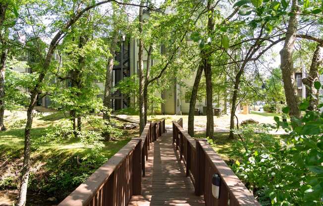 a wooden bridge in the middle of a park with trees