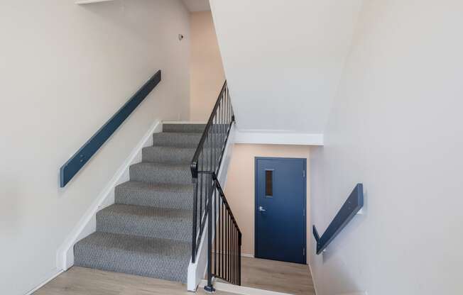 a staircase with a blue door at the bottom of the stairs