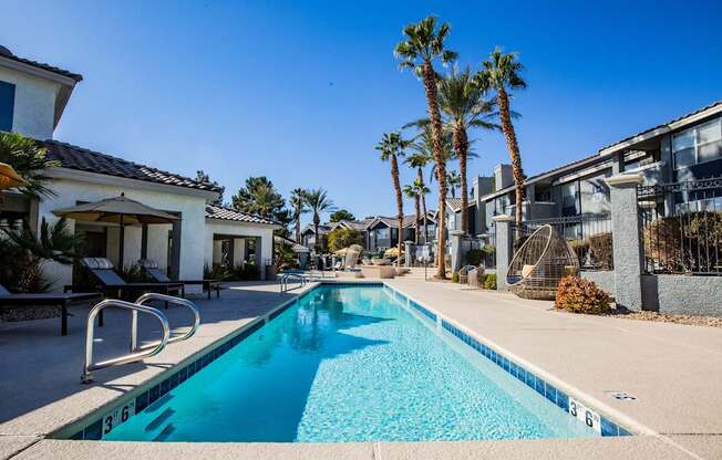 A swimming pool surrounded by palm trees and buildings.