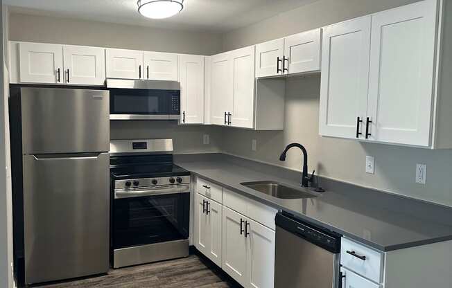 A modern kitchen with a stainless steel refrigerator and a wall-mounted oven.