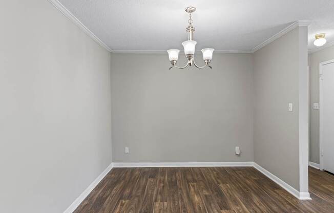 A room with wooden flooring and a chandelier.