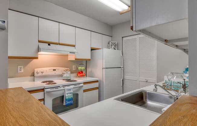 a kitchen with white cabinets and white appliances and a sink