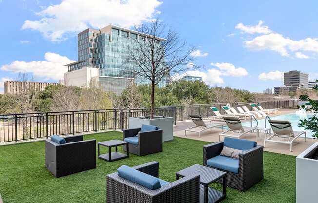 a rooftop patio with chairs and a pool and a city in the background