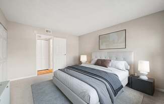 A bedroom with a large bed and a painting on the wall.