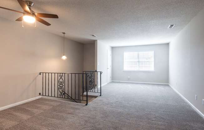 an empty living room with a ceiling fan and a window